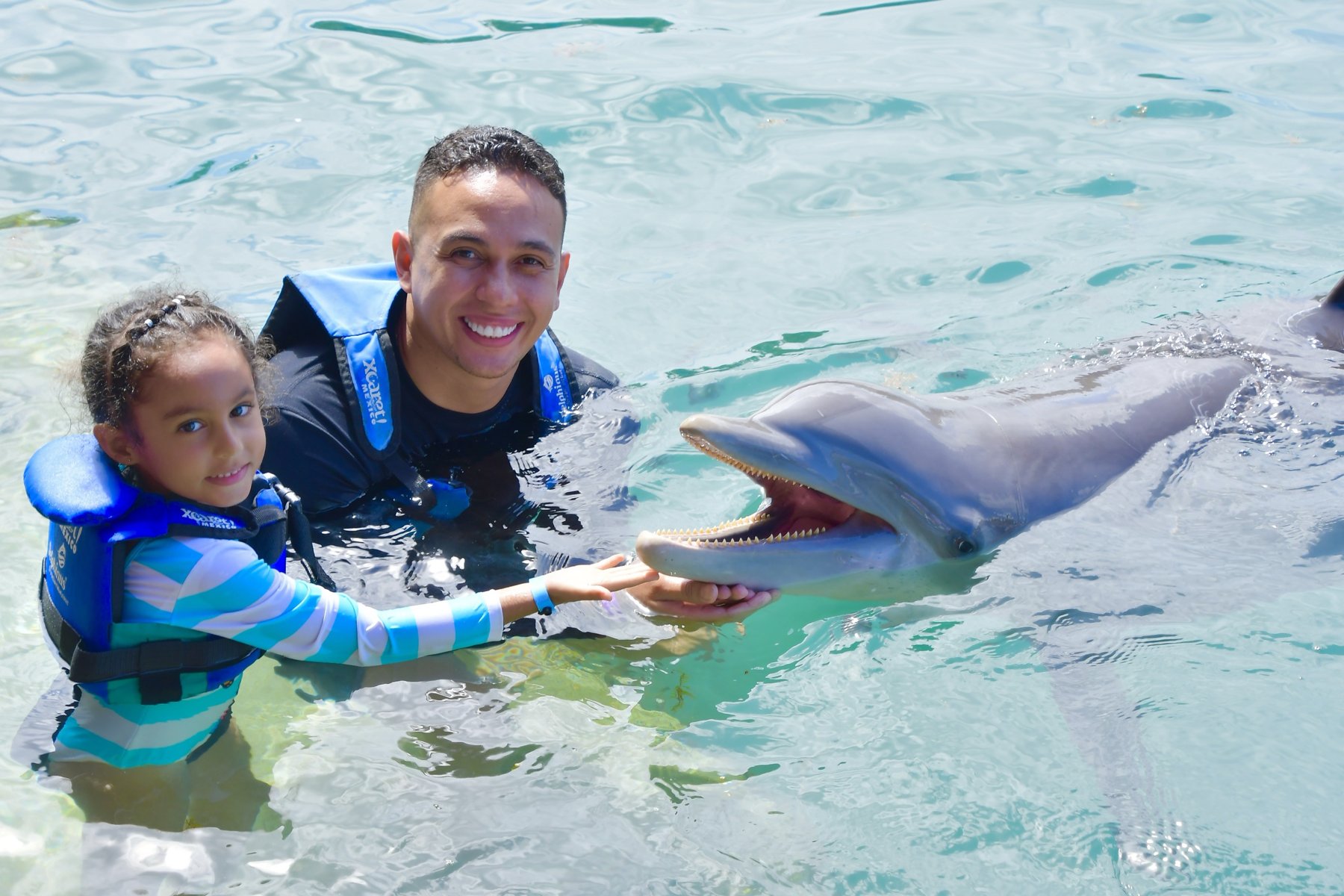 Padre e hija en el agua con un delfín