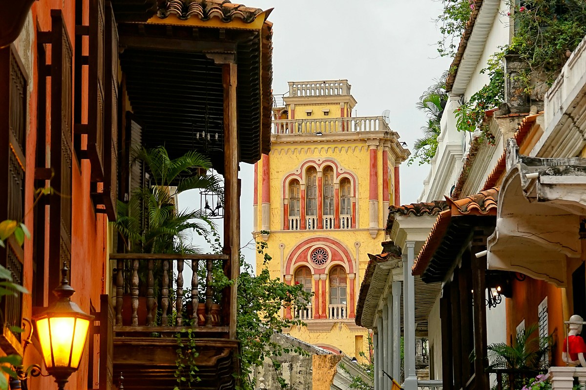 Calle colonial de Cartagena con balcones de madera y una torre amarilla al fondo
