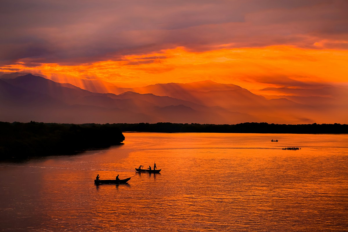 Pescadores en canoa al atardecer con la Sierra Nevada de Santa Marta al fondo